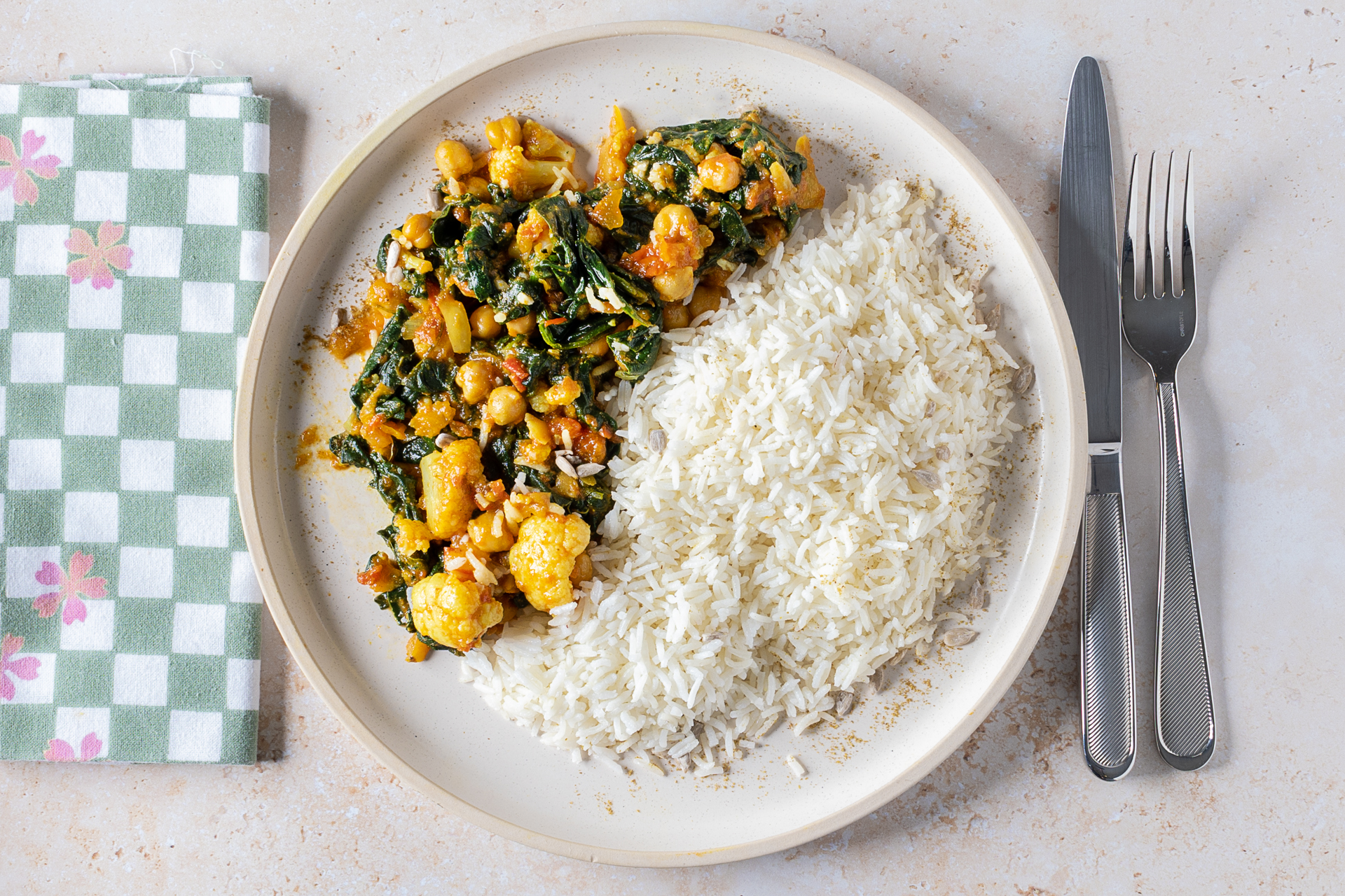 Chickpea and cauliflower curry served on a white plate with rice.