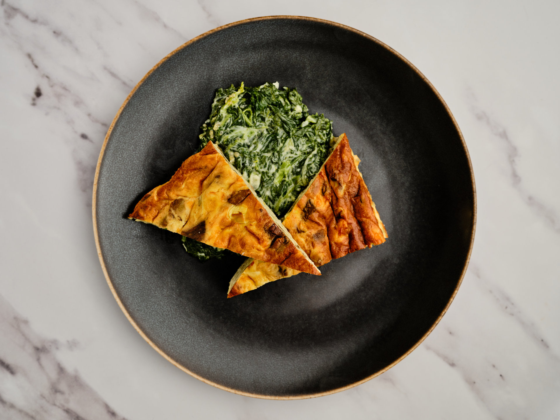 Omelette triangles with spinach on a black plate