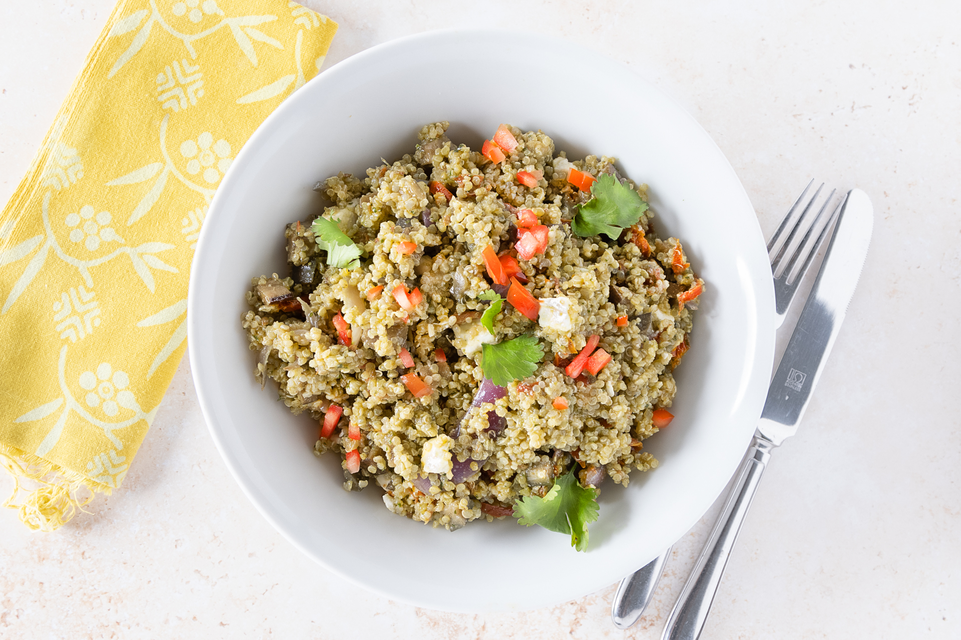 Quinoa, feta and aubergine salad in a bowl with a knife and fork