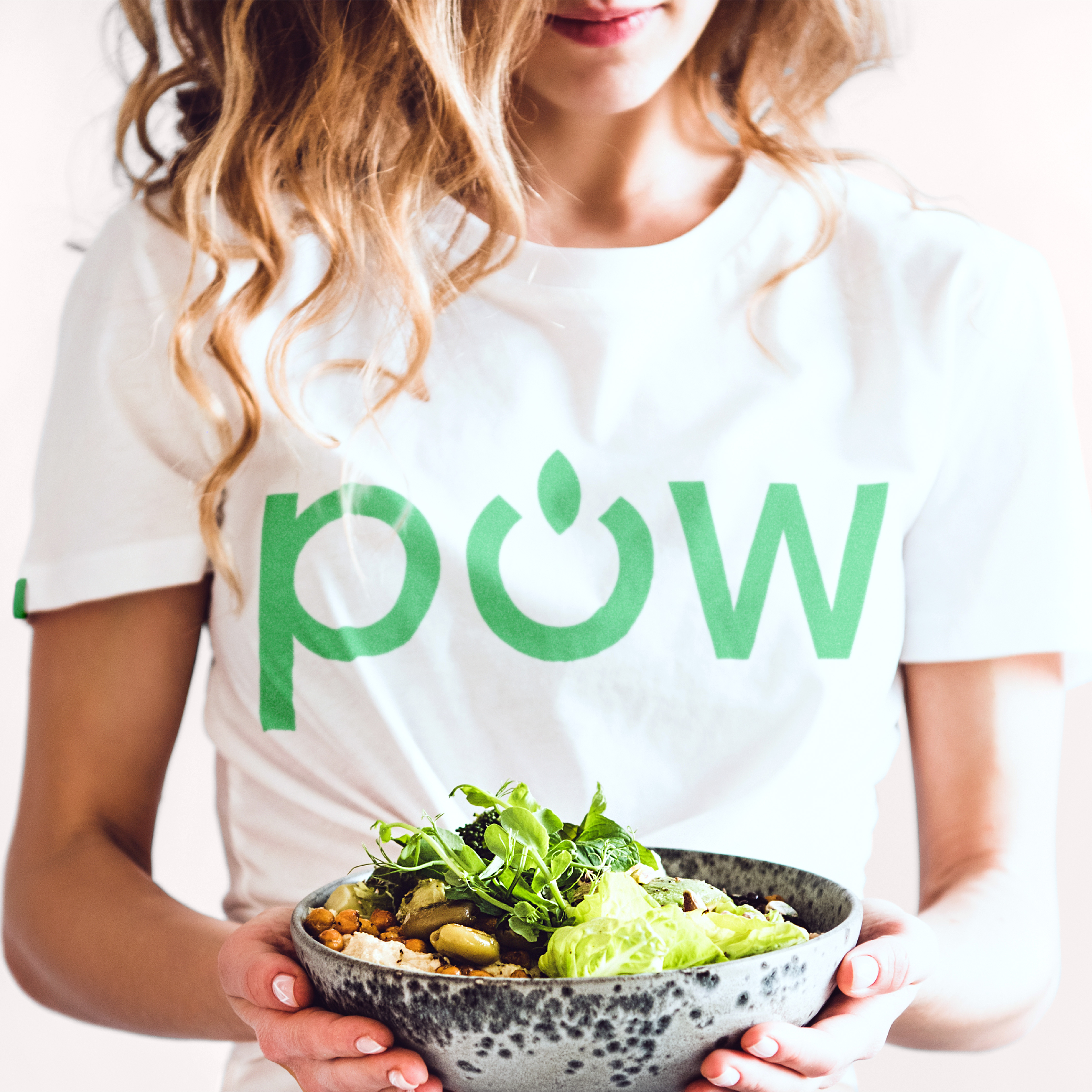 Young woman in a white t-shirt holding out a bowl of healthy food