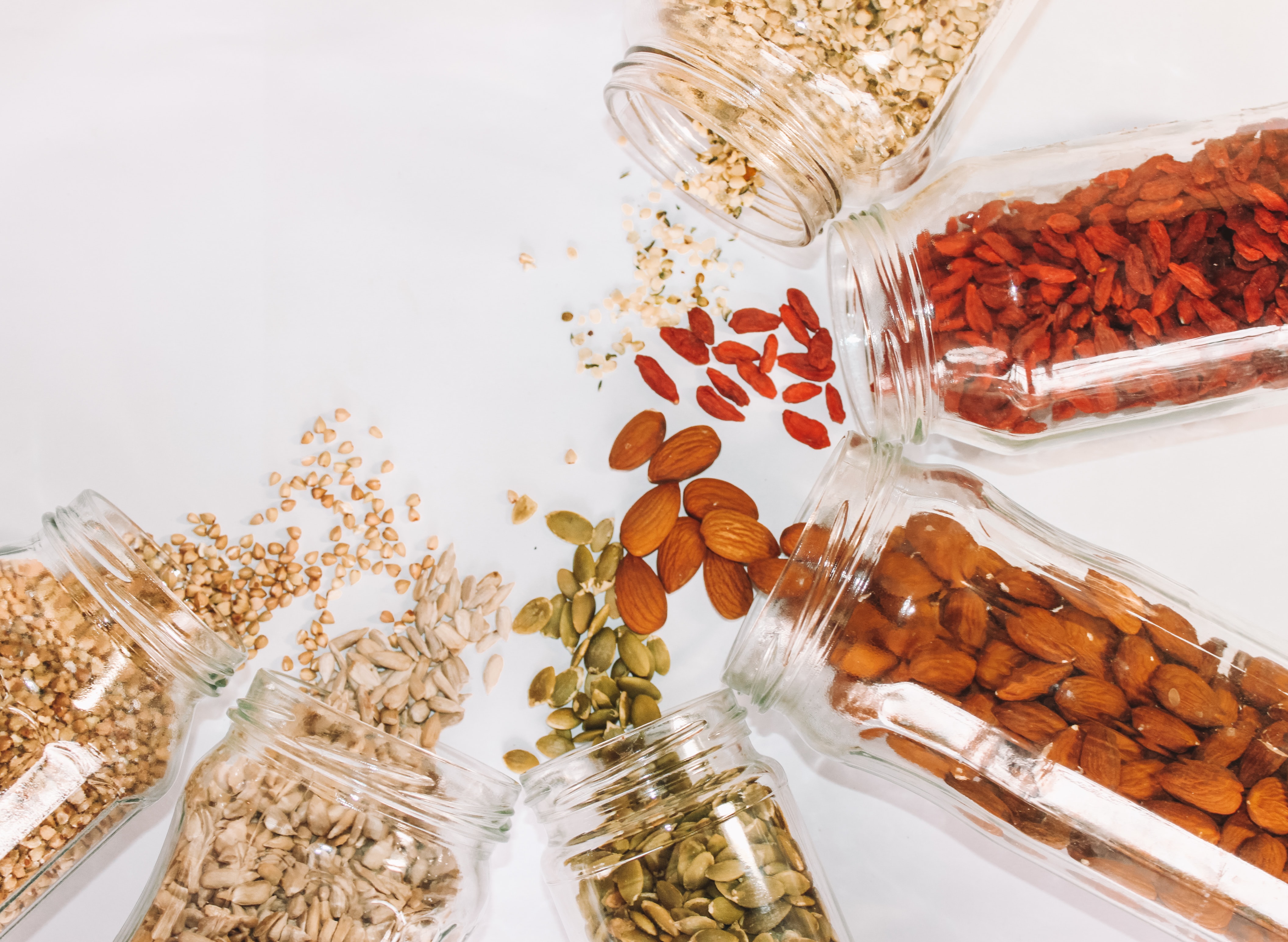 Nuts spilling out of 6 different jars in a semi circle