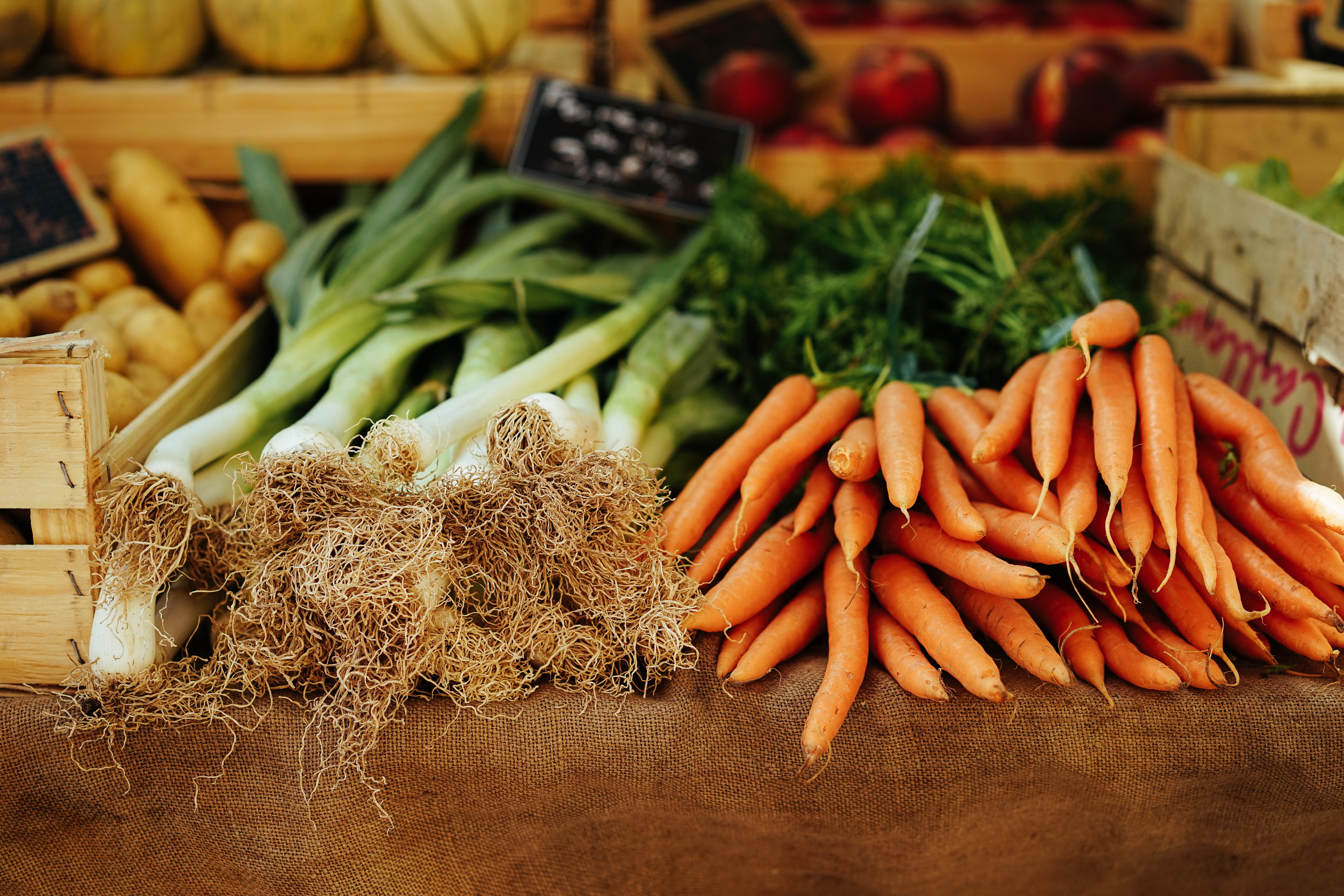 A pile of carrots and leeks on a wooden surface